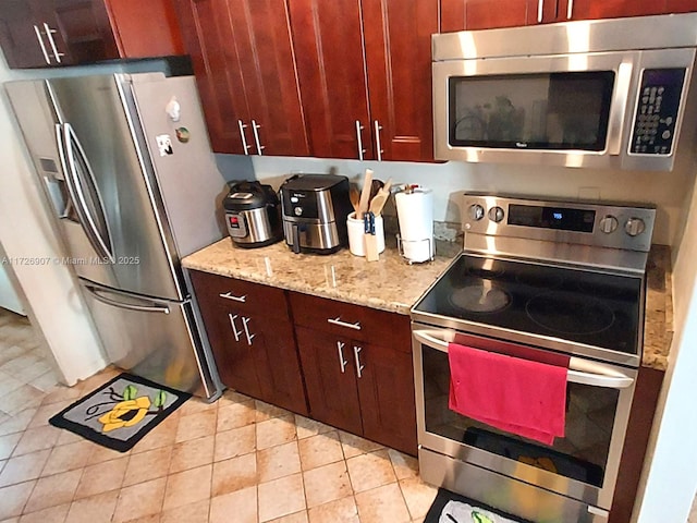 kitchen featuring light tile patterned floors, stainless steel appliances, and light stone counters