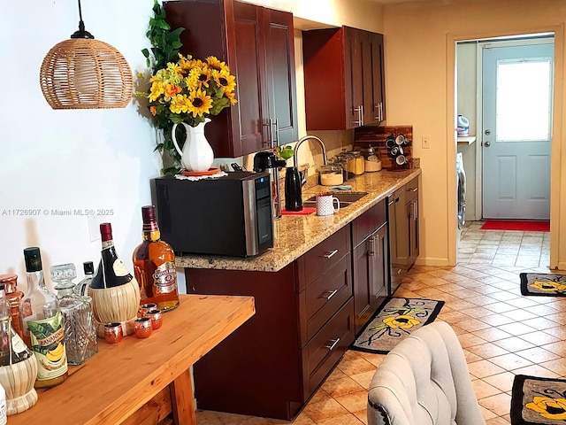 kitchen with light stone countertops, light tile patterned floors, pendant lighting, and sink