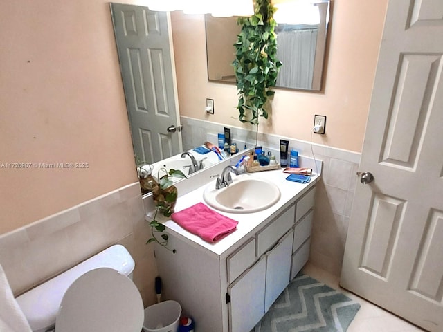 bathroom featuring toilet, vanity, tile walls, and tile patterned flooring