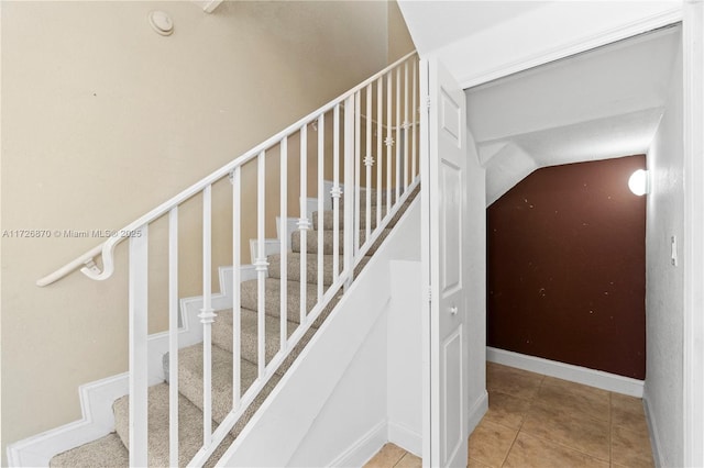 staircase with vaulted ceiling and tile patterned floors