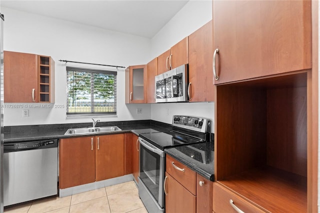 kitchen featuring light tile patterned floors, sink, dark stone countertops, and stainless steel appliances