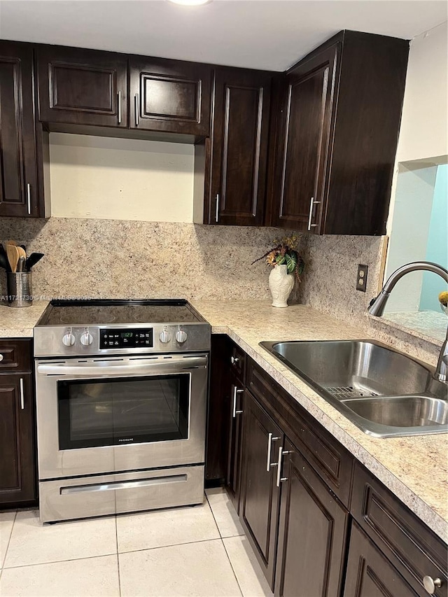 kitchen featuring light tile patterned floors, backsplash, stainless steel electric stove, dark brown cabinetry, and sink