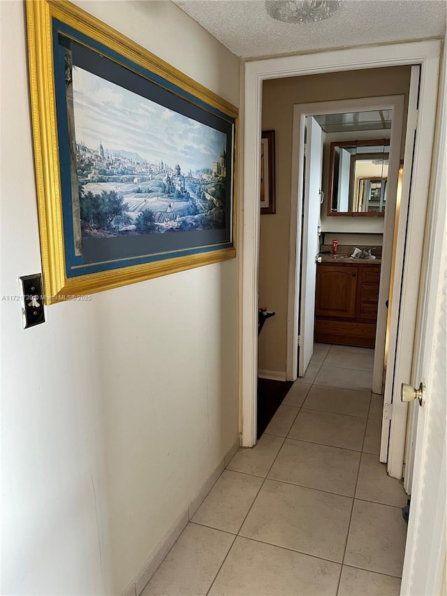 hallway with a textured ceiling and light tile patterned flooring