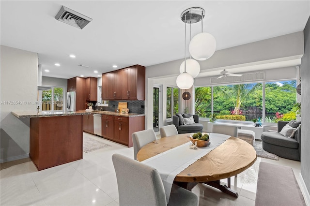 tiled dining space featuring ceiling fan, sink, and a wealth of natural light