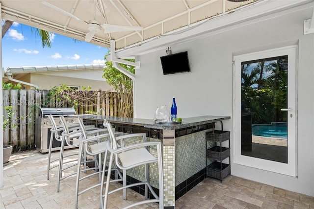 view of patio / terrace featuring ceiling fan, exterior bar, and area for grilling