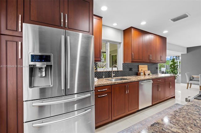 425 NE 29th St, Wilton Manors, FL 33334 - kitchen featuring stainless steel appliances, a sink, light stone countertops, backsplash, and light tile patterned flooring