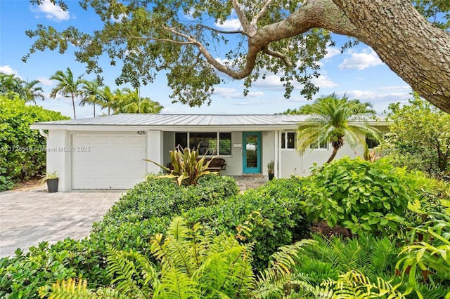425 NE 29th St, Wilton Manors, FL 33334 - ranch-style home featuring stucco siding, a garage, a standing seam roof, decorative driveway, and metal roof