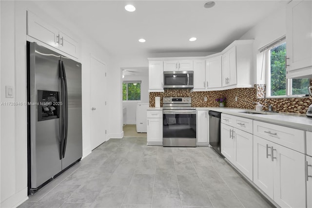 kitchen with plenty of natural light, stainless steel appliances, white cabinets, and sink