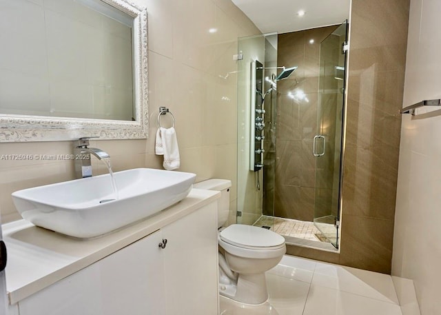 bathroom featuring toilet, a shower with shower door, tile patterned flooring, tile walls, and vanity