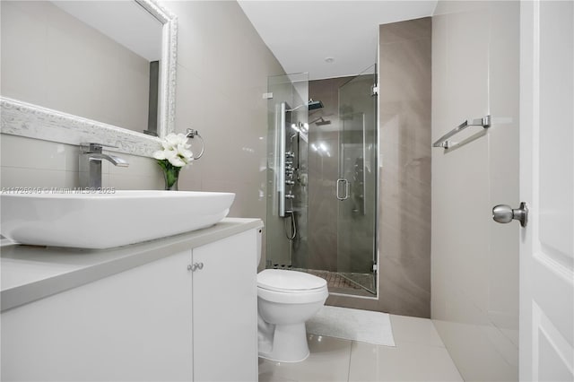 bathroom featuring a shower with shower door, toilet, vanity, and tile patterned flooring