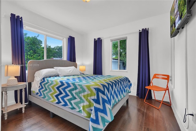 bedroom with multiple windows and dark hardwood / wood-style flooring