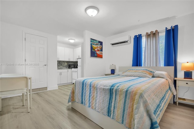 bedroom with light hardwood / wood-style floors and a wall unit AC