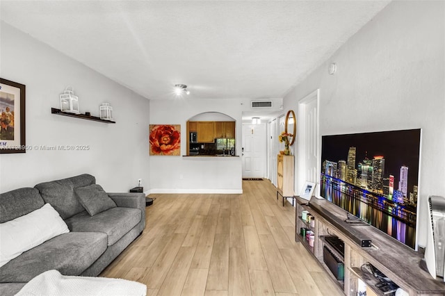 living room featuring light wood-type flooring and a textured ceiling