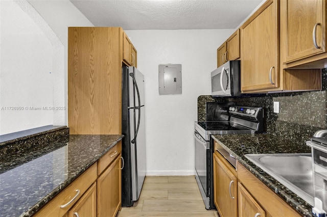 kitchen with dark stone countertops, electric panel, sink, a textured ceiling, and stainless steel appliances