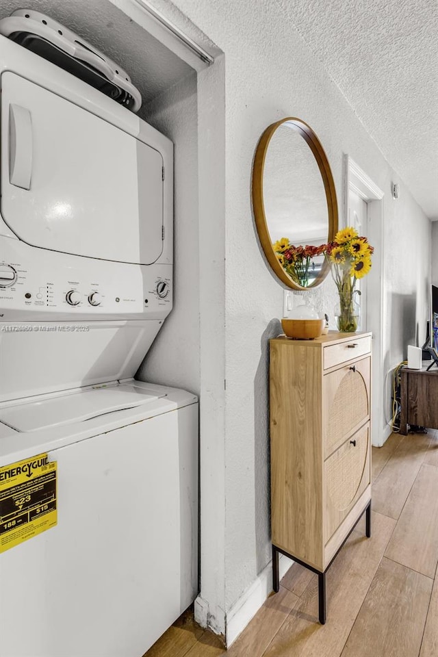 washroom featuring a textured ceiling and stacked washer / dryer