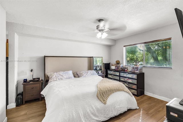 bedroom featuring ceiling fan, a textured ceiling, and light hardwood / wood-style flooring