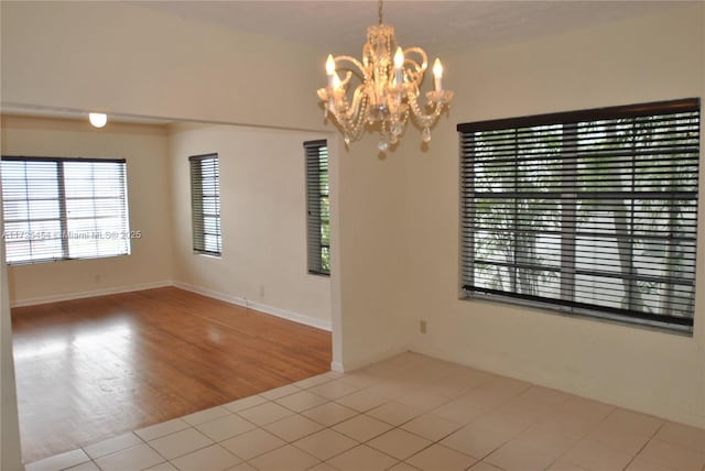 spare room featuring tile patterned floors and an inviting chandelier