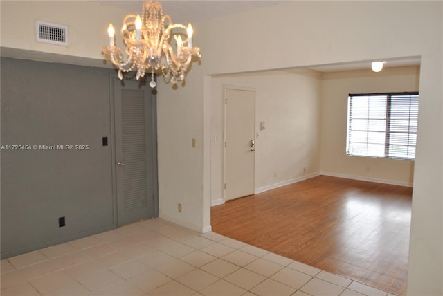 unfurnished room featuring an inviting chandelier and light tile patterned floors