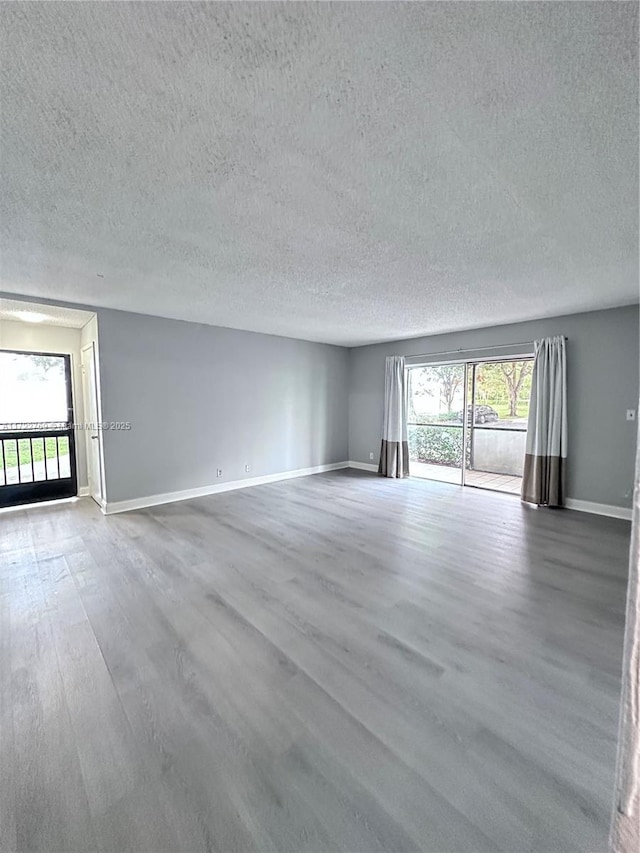 unfurnished room featuring wood-type flooring, a wealth of natural light, and a textured ceiling