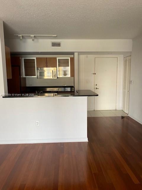 kitchen featuring dark hardwood / wood-style flooring, a textured ceiling, and rail lighting