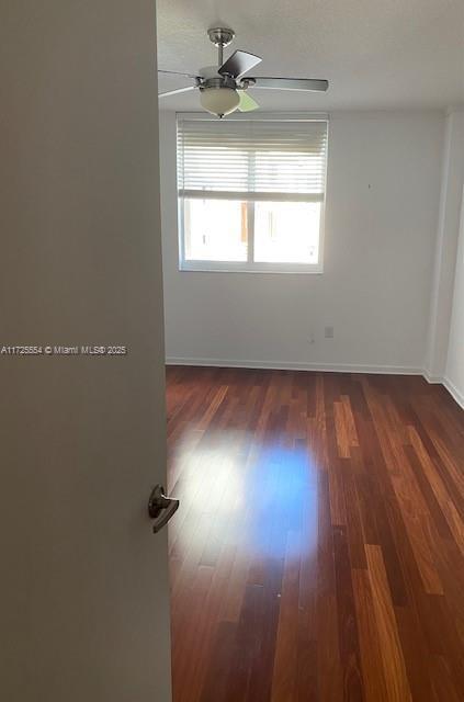 unfurnished room featuring ceiling fan and dark hardwood / wood-style flooring