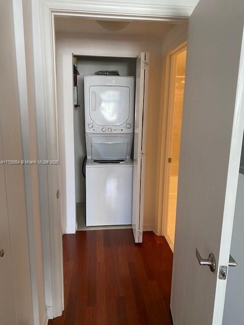 hallway featuring dark wood-type flooring and stacked washer and clothes dryer