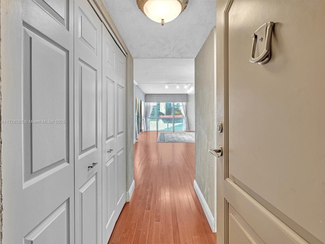 hall with light wood-type flooring and a textured ceiling