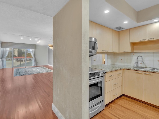 kitchen with light hardwood / wood-style floors, appliances with stainless steel finishes, decorative backsplash, light brown cabinetry, and sink