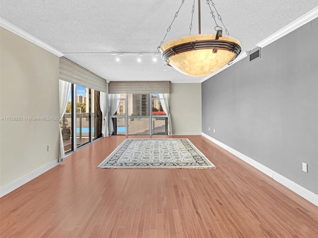 interior space with hardwood / wood-style flooring, a textured ceiling, and ornamental molding