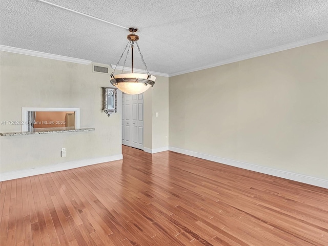 unfurnished room with a textured ceiling, crown molding, and hardwood / wood-style flooring