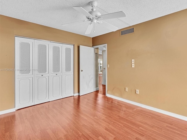 unfurnished bedroom featuring light wood-type flooring, ceiling fan, and a textured ceiling