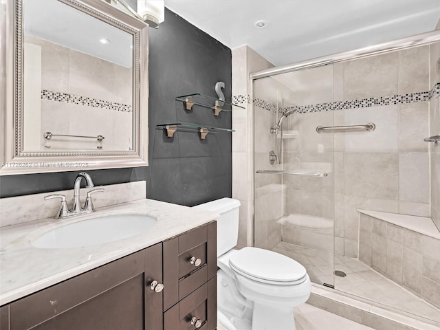 bathroom with toilet, vanity, and a shower with shower door