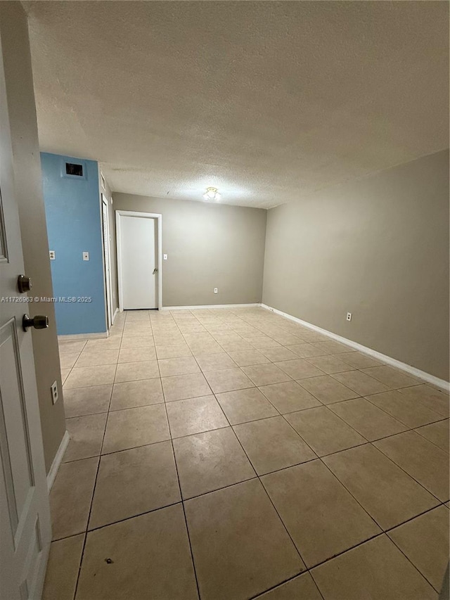 tiled spare room featuring a textured ceiling