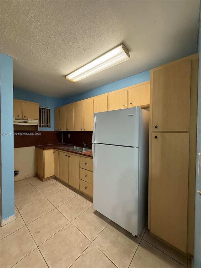 kitchen featuring light tile patterned floors, white refrigerator, light brown cabinets, and sink