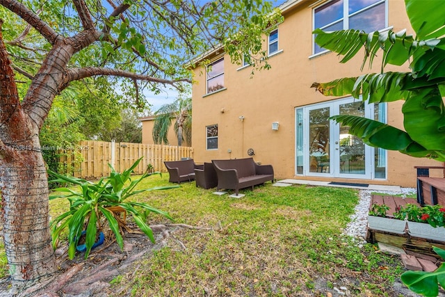 rear view of property featuring a lawn, an outdoor living space, and french doors