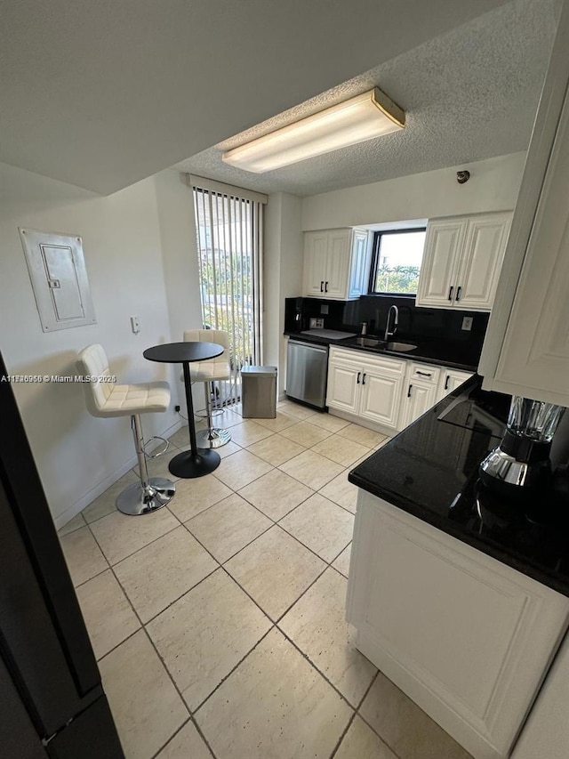 kitchen with sink, white cabinetry, stainless steel dishwasher, and plenty of natural light