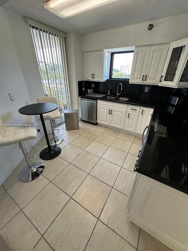 kitchen featuring stainless steel dishwasher, sink, and white cabinetry