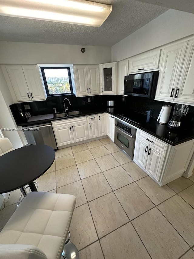 kitchen featuring stainless steel oven, backsplash, white cabinets, and sink