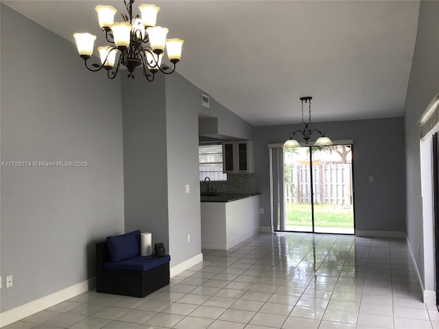 unfurnished dining area with an inviting chandelier, light tile patterned flooring, lofted ceiling, and sink