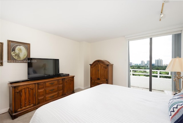 bedroom featuring baseboards, light colored carpet, and access to exterior