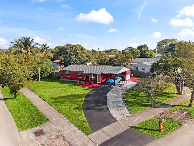 single story home with a front yard, driveway, and metal roof