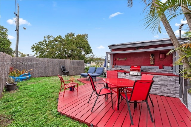 wooden terrace with area for grilling, a yard, and an outdoor kitchen