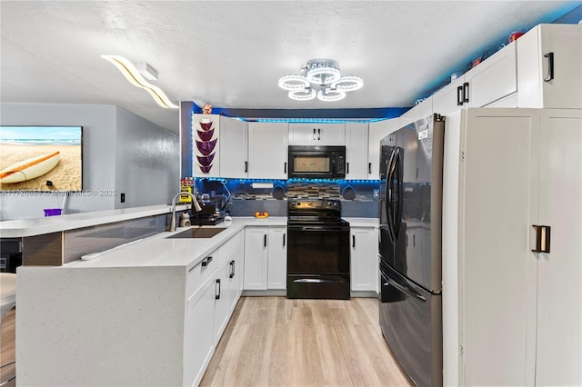 kitchen with black appliances, sink, white cabinets, kitchen peninsula, and light hardwood / wood-style flooring