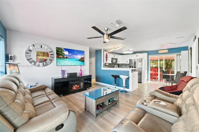 living room featuring a fireplace, light hardwood / wood-style floors, and ceiling fan