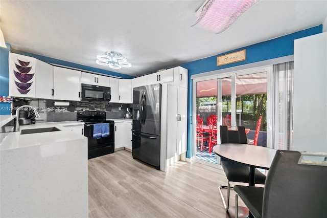 kitchen featuring sink, black appliances, light wood-type flooring, backsplash, and white cabinets