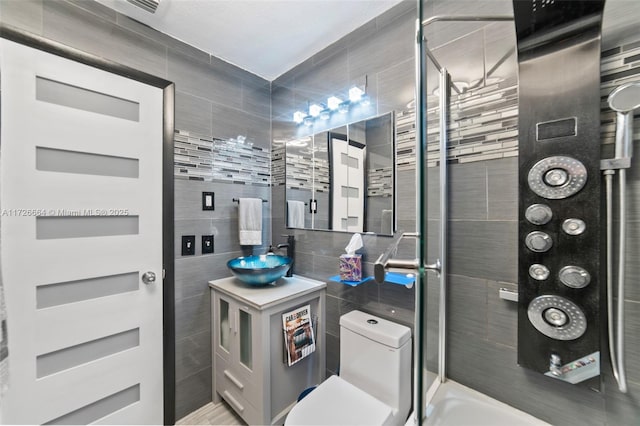 bathroom featuring tile walls, sink, toilet, and tiled shower