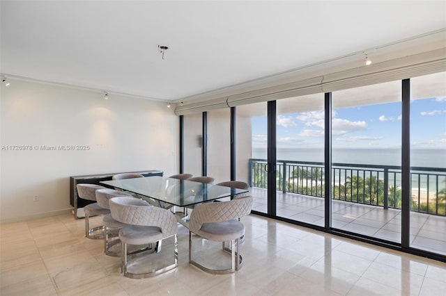 dining space with track lighting, light tile patterned floors, a wall of windows, and a water view