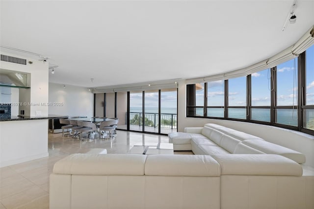 tiled living room with a wall of windows, track lighting, and a water view