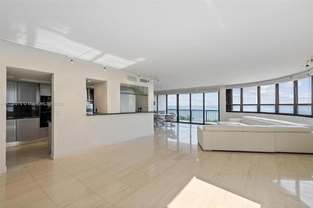 unfurnished living room featuring a wall of windows, a water view, and light tile patterned flooring