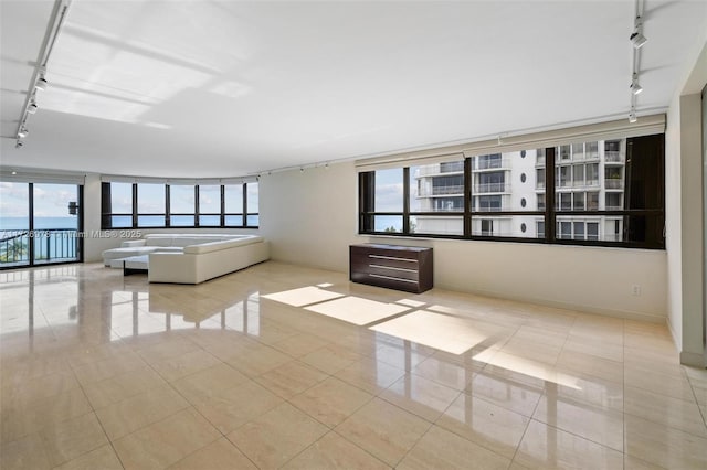 unfurnished living room with light tile patterned floors, plenty of natural light, and track lighting